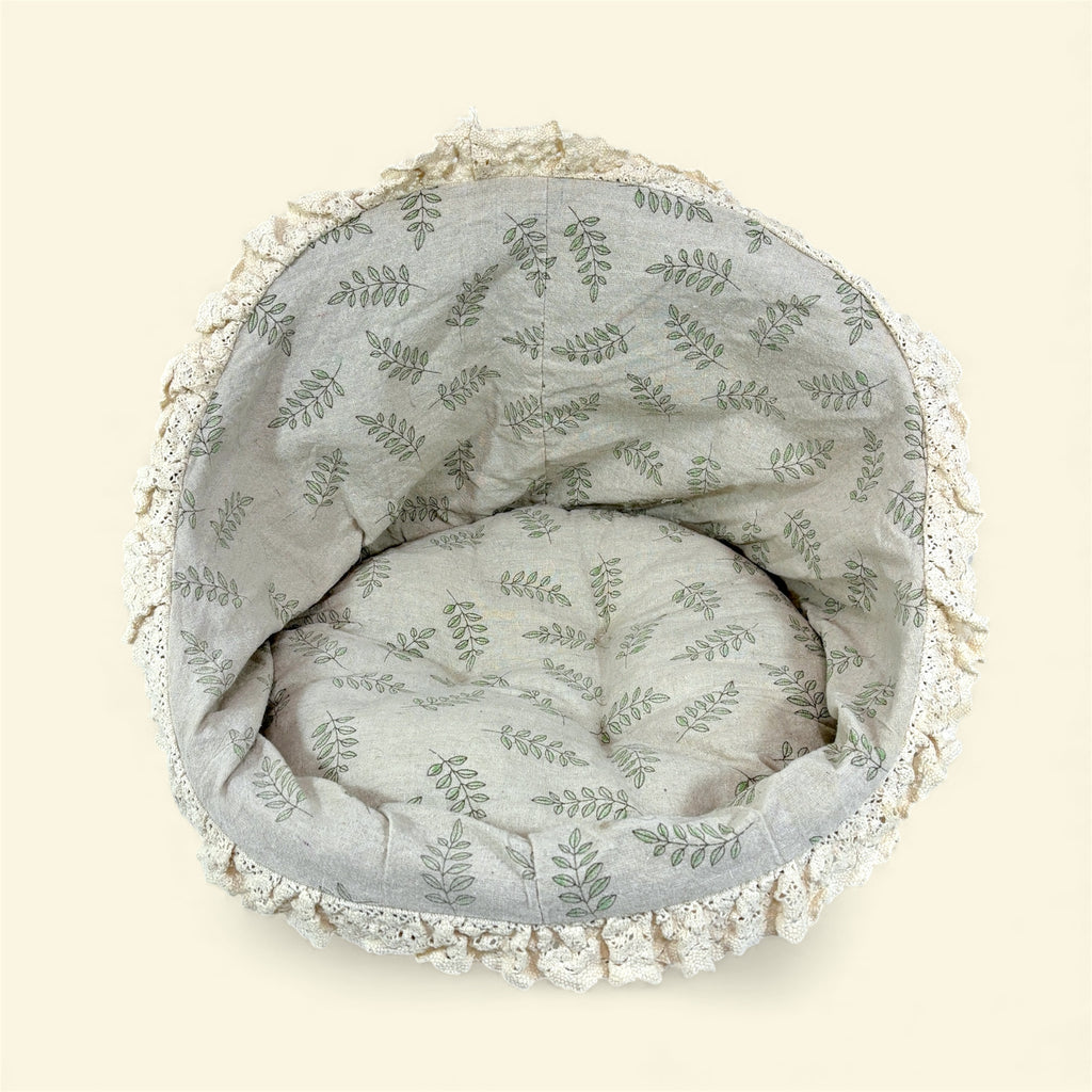 Round wicker pet bed with leaf pattern on a beige background