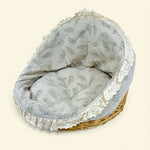 Load image into Gallery viewer, Wicker pet bed with floral patterned cover on a beige background
